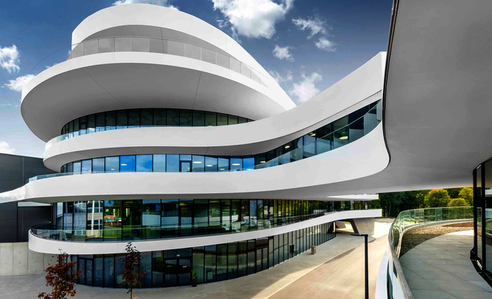 Ein ästhetisch geschwungener Baukörper aus Stahlbeton, der den Eindruck dynamischer Bewegung entstehen lässt. Für die einzelnen Geschosse wurden nach den Geometrien der Architekten unterschiedlich große weiße Betonplatten vor Ort gegossen.