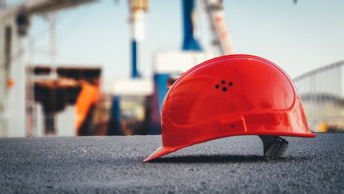 Roter Helm liegt auf dem Asphalt einer Baustelle