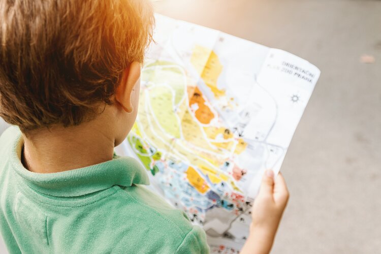 Blick über die Schulter eines Grundschülers, der eine bunte gemalte Karte in der Hand hält