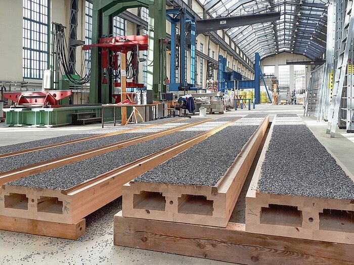 In der Peter-Behrens-Halle, der Versuchshalle der Bauingenieure der TU Berlin, wurde der neue Holz-Beton-Verbund erforscht: Im Vordergrund sieht man Holzelemente, auf die ein Granulatsplitt aufgetragen wurde. Darauf wird der Beton gegossen. Es entsteht eine sehr tragfähige Verbindung.