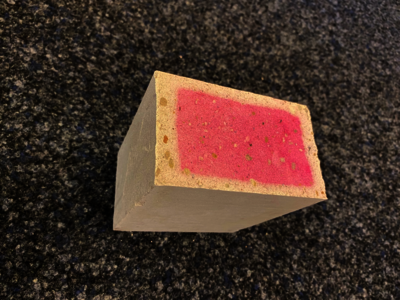 Stein auf Boden: Steinoberfläche mit roter Fläche, Nachweis des Prozesses der Recarbonatisierung im Kalksandstein durch Phenolphthalein.