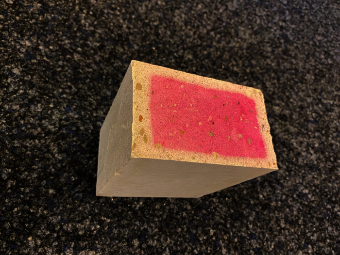 Stein auf Boden: Steinoberfläche mit roter Fläche, Nachweis des Prozesses der Recarbonatisierung im Kalksandstein durch Phenolphthalein.