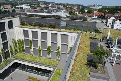 Mehrgeschossige moderne Wohnanlage mit begrünten Dach- und Fassadenflächen mit Solarpanels und Terrassenbereich