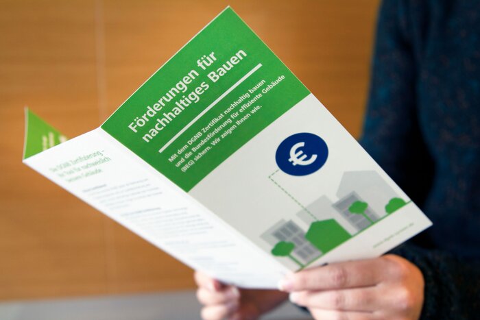 Eine Person hält eine Broschüre der DGNB zur Förderung in den Händen