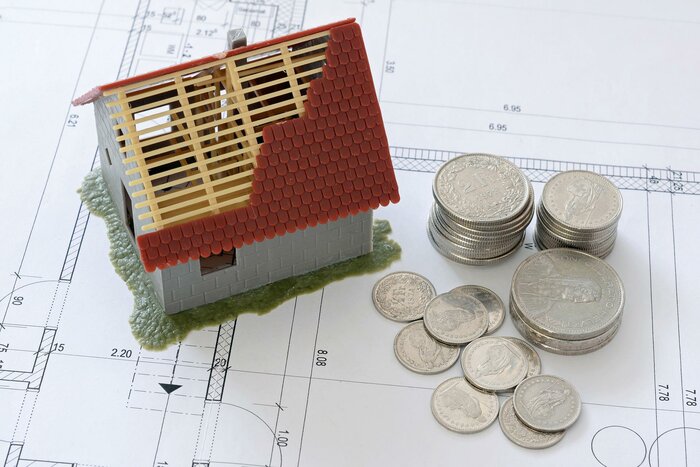 Hausmodell neben Geldmümnzen
