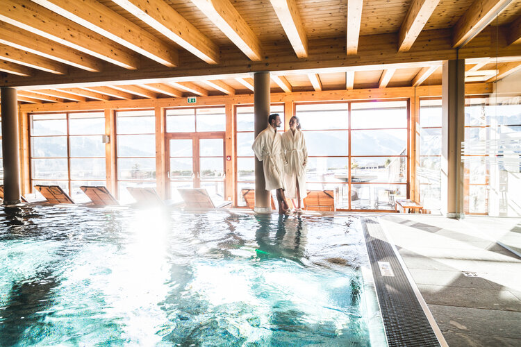Spa-Bereich mit Holzausstattung, Schwimmbecken und Terrassenfenstern im Naturhotel Edelweiss Wagrain