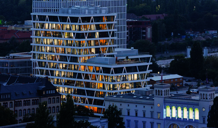 Einzelne Stützen der Fassade werden am Abend sinuskurvenartig beleuchtet