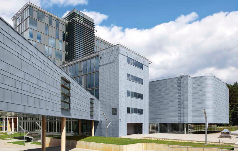 Ansicht von Südwesten: Die Verbindungsbrücke bindet den Altbau an den Neubau an; in der Mitte befindet sich der Wissenschaftstrakt, rechts das Veranstaltungszentrum, oben links der Verwaltungsriegel.