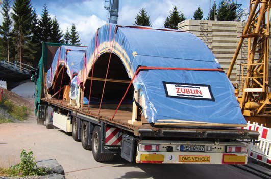 Für den Transport aus dem Züblin-Timber-Werk in Aichach wurden den geschwungenen Elementen vier hölzerne Stützenfüße montiert.