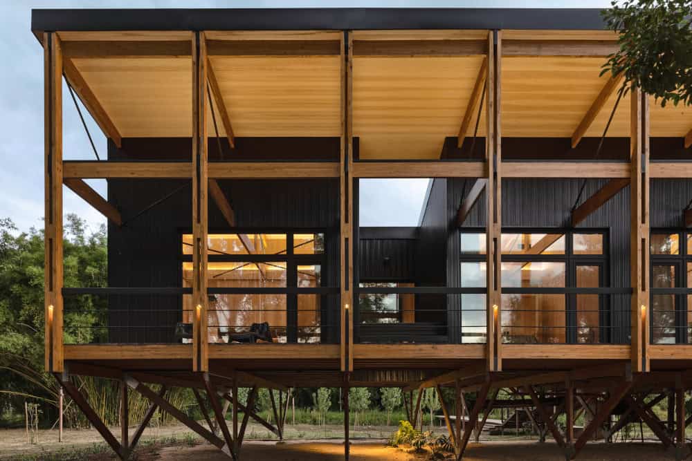 Die Haus-in-Haus Konstruktion erlaubt großzügige Freiflächen unter dem schützenden Pultdach. Die Kunststoff-Fenster aus dem System Schüco LivIng 82 MD sind mit einer schwarzen Folierung optisch perfekt in die ebenso schwarzen Holzaußenwände integriert. © Fotograf: Leonardo Finotti // Nutzungsrecht: Schüco International KG
