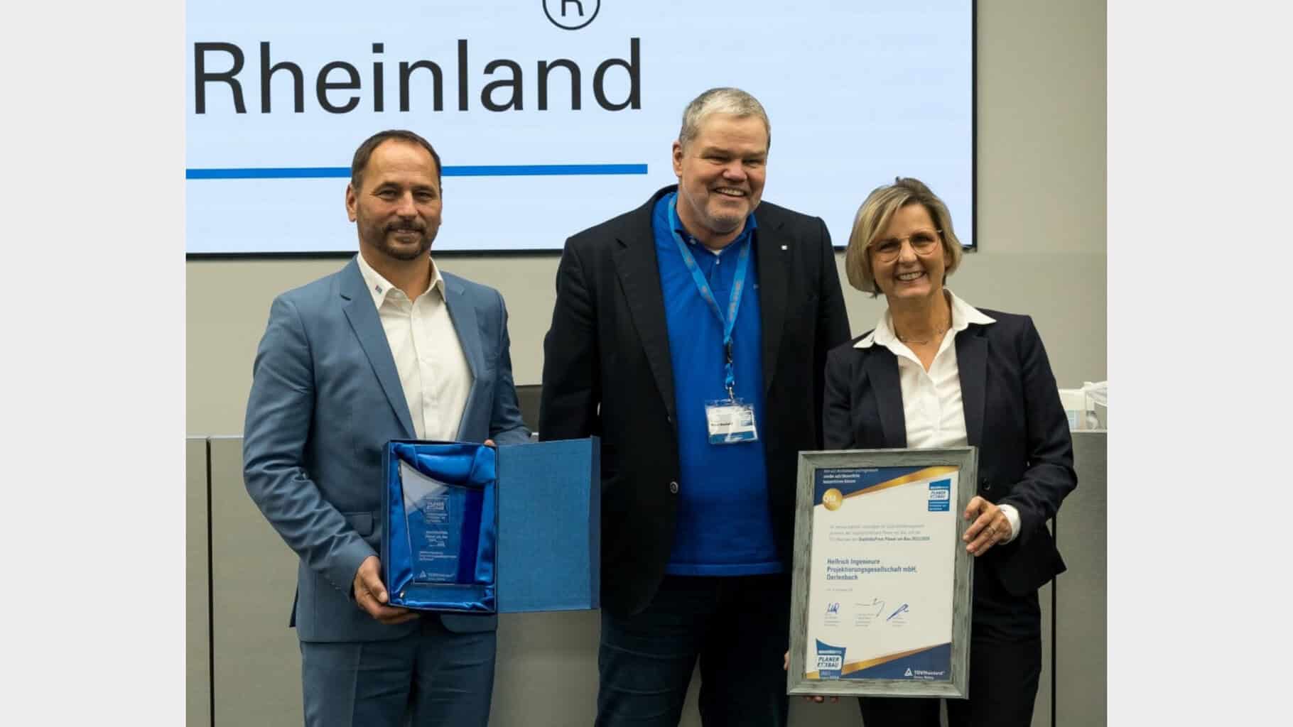 Cordula Helfrich (rechts) und Wilfried Helfrich (links) erhalten den QualitätsPreis Planer am Bau 2025/2026 von Dr.-Ing. Knut Marhold vom QualitätsVerbund © QualitätsVerbund Planer am Bau