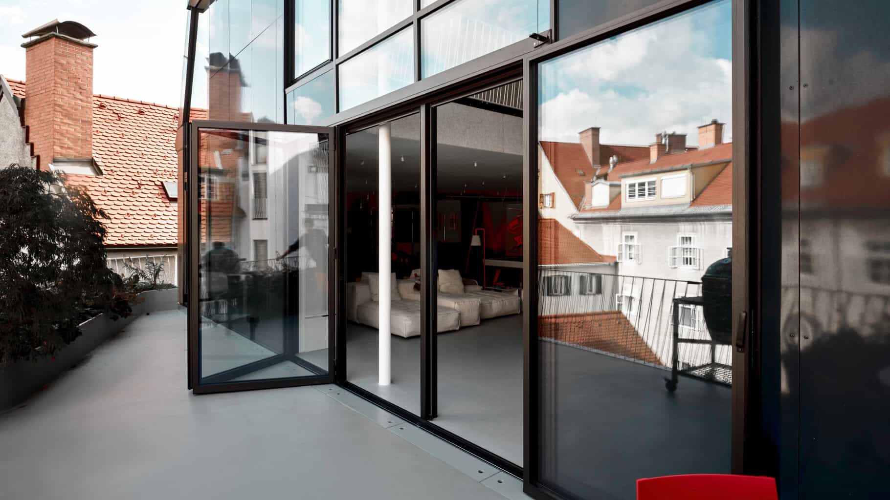 Geöffnete Glas-Faltwände und ein durchgehender Bodenbelag verbinden Innen und Außen zu einem Raum. © Stefan Leitner