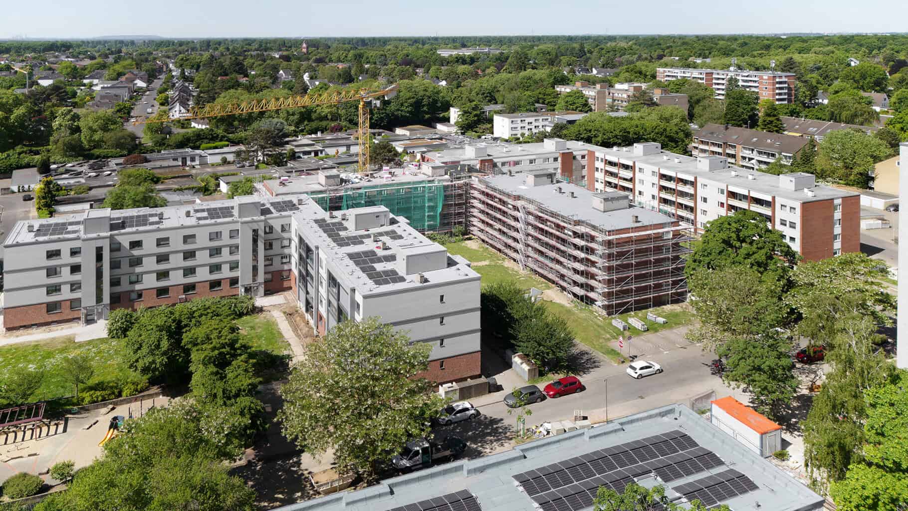 Im Corelli-Quartier in Düsseldorf werden 140 Wohnungen seriell saniert. Der Gebäuderiegel in der Bildmitte ist bereits fertig gestellt, der rechts daneben im Bau. Ganz rechts ist der unsanierte Zustand erkennbar. © Lioba Schneider / Schüco International KG