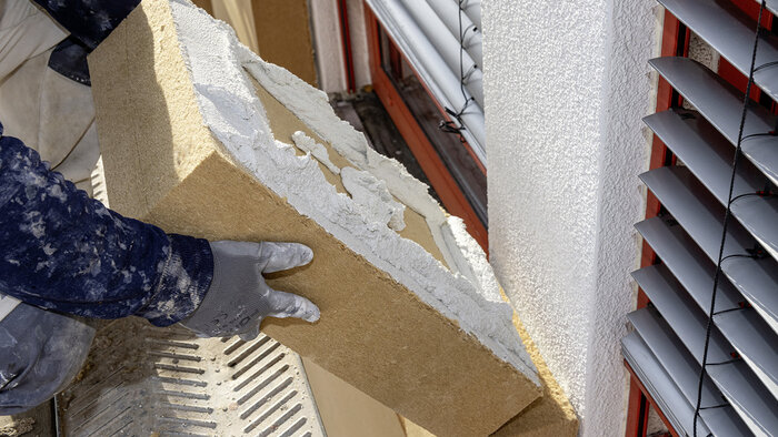Aufgrund ihrer kompakten Maße kann die Holzfaserdämmplatte auf der Baustelle mühelos von einer Person verarbeitet werden – wie hier bei einer Fassadendämmung mit dem Gutex Thermowall-WDVS. © GUTEX