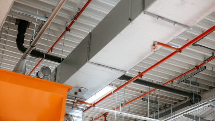 Die Entwässerung läuft unter dem Hallendach über Sammelleitungen als Druckentwässerung in schmalen Rohren (DN 70). (Die roten Leitungen sind Sprinkler © Loro