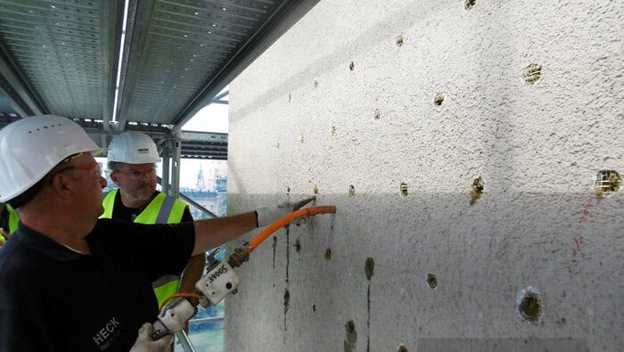 Der Klebemörtel wird punktuell mittels Klebepistole zwischen Wand und Bestandsdämmung eingespritzt. Hierdurch entsteht eine dauerhafte Verbindung zwischen Untergrund und Alt-WDVS. © Heck Wall Systems