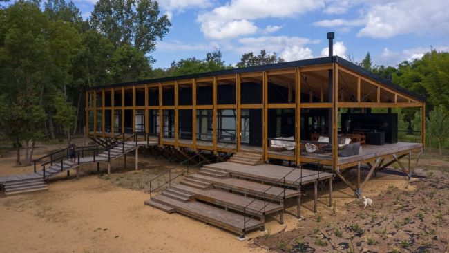 Die Konstruktion steht auf Holzbinderstützen, um es vor den periodisch auftretenden Überschwemmungen zu schützen. Großzügige Holztreppen mit breiten Podesten führen zum Bootsanleger und in das Innere der Insel. © Fotograf: Leonardo Finotti // Nutzungsrecht: Schüco International KG