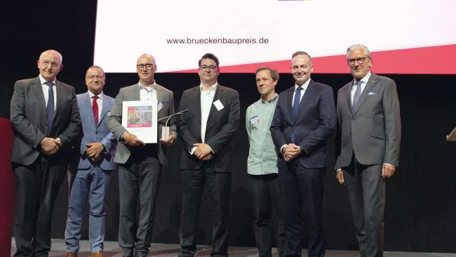 Preisverleihung beim Deutscher Brückenbaupreis 2023 (v.l.n.r.): Dr.-Ing. Heinrich Bökamp (Präsident BIngK), MR Prof. Dr.-Ing. Gero Marzahn (BMDV), Dr.-Ing. SFI Christian Böttcher (panta ingenieure), Dipl.-Ing. Architekt Enrico Kleinke (studioH2K Architekten), Dipl.-Ing. Arch. Alexandre Rombourg (HHLA Immobilien, Bauherrenvertreter), Dr. Volker Wissing (Bundesminister für Digitales und Verkehr), Dipl.-Ing. Jörg Thiele (Präsident VBI) (Foto: Yerko Romero Viveros)