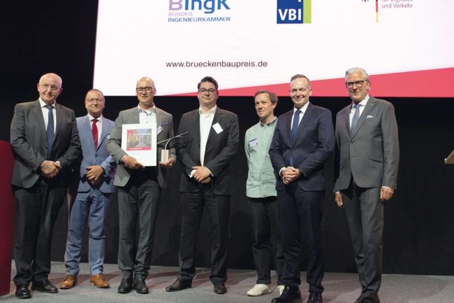 Preisverleihung beim Deutscher Brückenbaupreis 2023 (v.l.n.r.): Dr.-Ing. Heinrich Bökamp (Präsident BIngK), MR Prof. Dr.-Ing. Gero Marzahn (BMDV), Dr.-Ing. SFI Christian Böttcher (panta ingenieure), Dipl.-Ing. Architekt Enrico Kleinke (studioH2K Architekten), Dipl.-Ing. Arch. Alexandre Rombourg (HHLA Immobilien, Bauherrenvertreter), Dr. Volker Wissing (Bundesminister für Digitales und Verkehr), Dipl.-Ing. Jörg Thiele (Präsident VBI) (Foto: Yerko Romero Viveros)