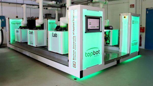 Die grüne Beleuchtung zeigt, dass die Roboter einsatzbereit sind und alles sicher ist. Sobald jemand zu nah an einem der Roboterarme steht, schaltet die Beleuchtung auf rot und die Roboter stoppen. © Judith Merkelt-Jedamzik / HSBO