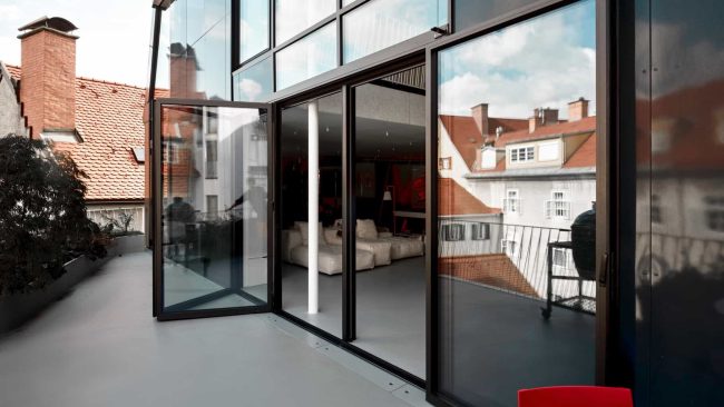 Geöffnete Glas-Faltwände und ein durchgehender Bodenbelag verbinden Innen und Außen zu einem Raum. © Stefan Leitner