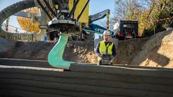 Mit einer Reichweite von bis zu 26 Metern und einer Druckgeschwindigkeit von bis zu 10 Zentimetern pro Sekunde entstehen direkt auf der Baustelle tragende Betonwände Schicht für Schicht. © Aleksej Keksel