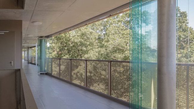 Die schützende Glasfassade vor den Laubengängen lässt sich über die gesamte Länge öffnen. Dafür werden die Proline T-Verglasungen um 90 Grad eingedreht und als unauffällige Glaspa-kete an den Stützen geparkt. © Till Schuster