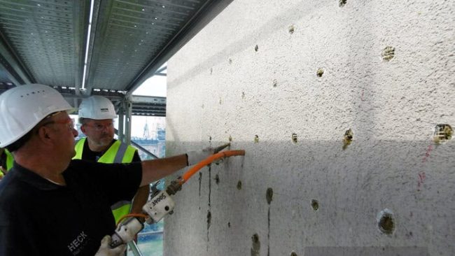 Der Klebemörtel wird punktuell mittels Klebepistole zwischen Wand und Bestandsdämmung eingespritzt. Hierdurch entsteht eine dauerhafte Verbindung zwischen Untergrund und Alt-WDVS. © Heck Wall Systems