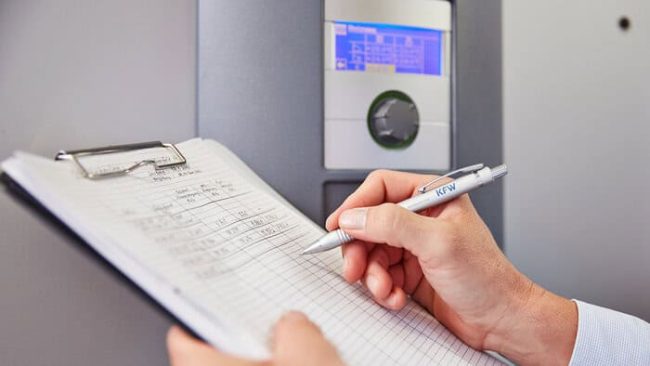 Ein Energieberater der KfW beim Kontrollieren der Heizungsanlage eines Niedrigenergiehauses © KfW-Bildarchiv / Jens Steingässer